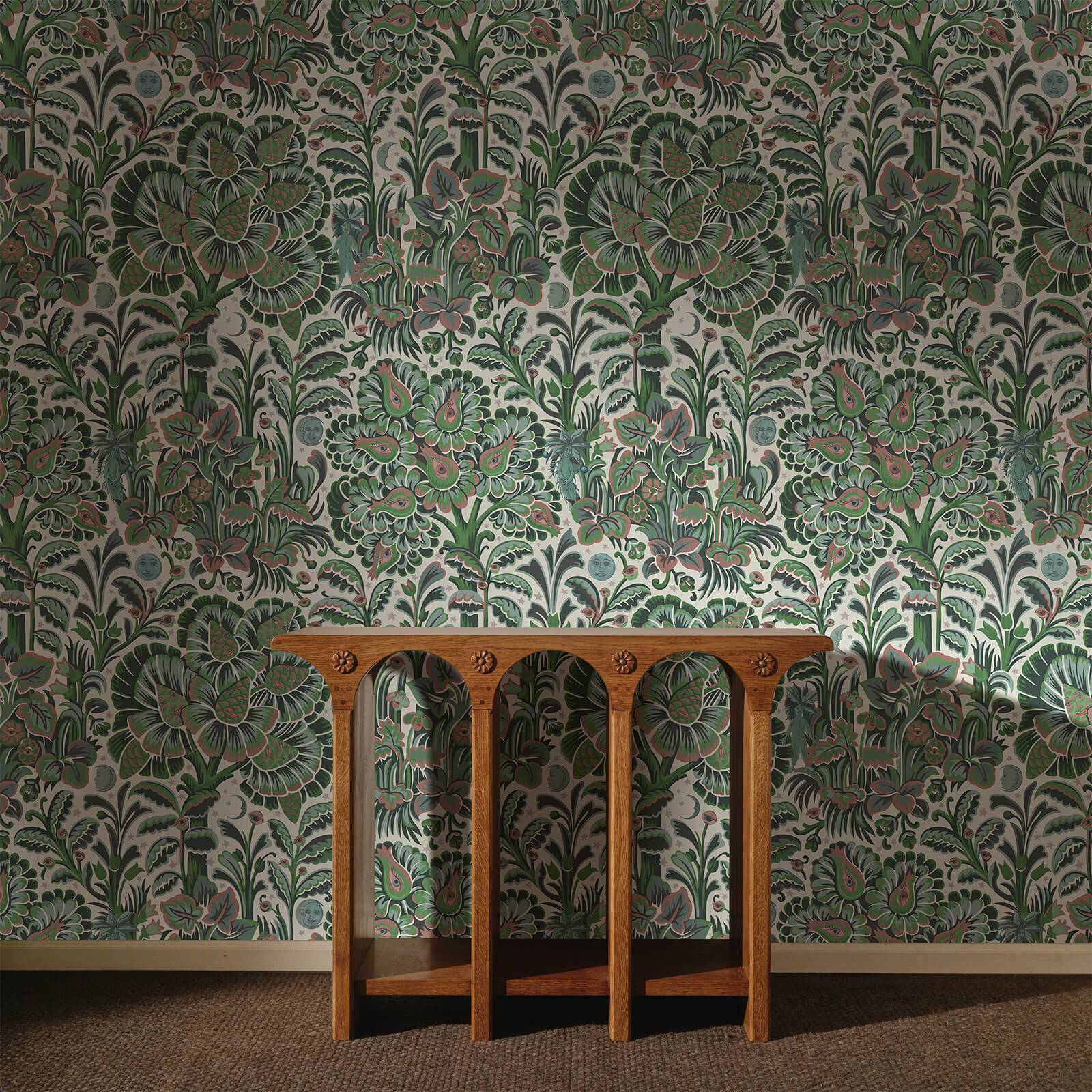 a wooden table in front of a wall with floral wallpaper
